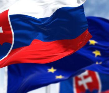 Detail of the national flag of Slovakia waving in the wind with blurred european union flag in the background on a clear day. Democracy and politics. European country.