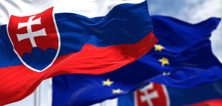 Detail of the national flag of Slovakia waving in the wind with blurred european union flag in the background on a clear day. Democracy and politics. European country.